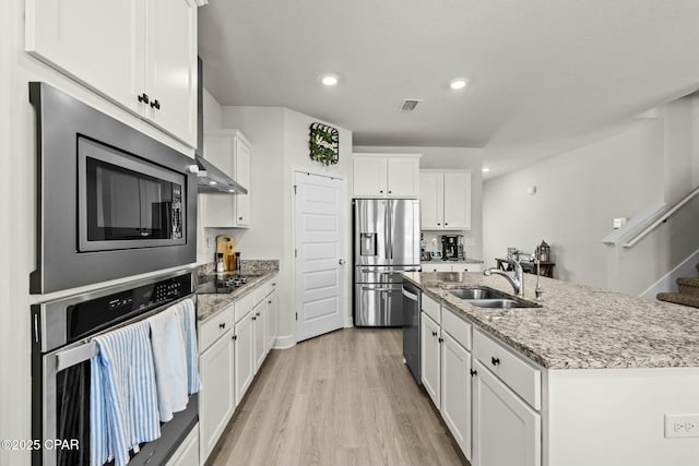 kitchen featuring white cabinets, a sink, light wood-style floors, stainless steel appliances, and visible vents