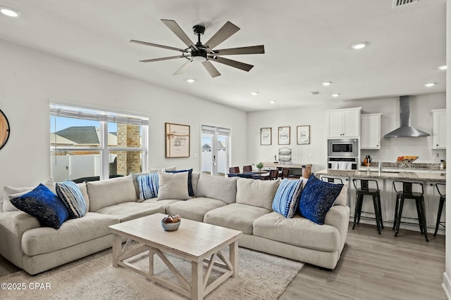 living area with recessed lighting, a ceiling fan, visible vents, and light wood-type flooring