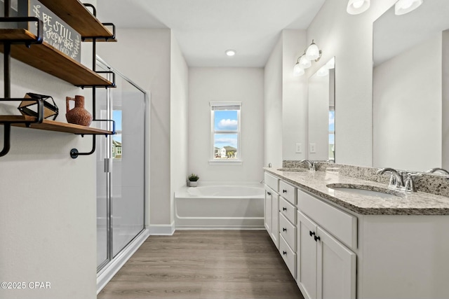 full bathroom with a shower stall, a sink, a bath, and wood finished floors