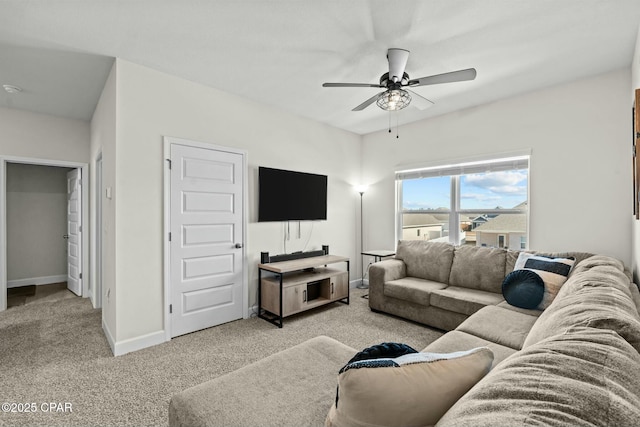 living room with a ceiling fan, baseboards, and light carpet