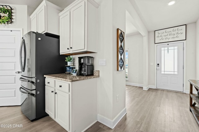 kitchen featuring baseboards, stone countertops, and light wood finished floors