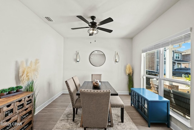 dining room featuring visible vents, a ceiling fan, baseboards, and wood finished floors
