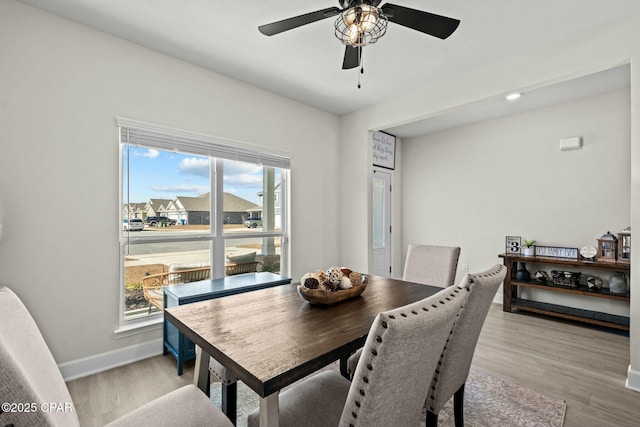 dining space featuring light wood-type flooring, baseboards, and ceiling fan