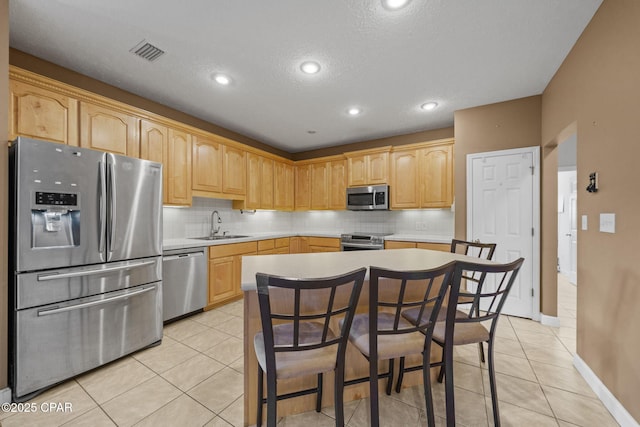 kitchen featuring tasteful backsplash, appliances with stainless steel finishes, light brown cabinetry, and visible vents