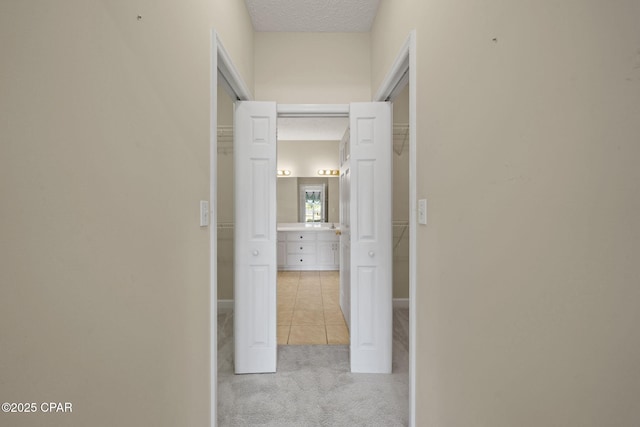 hall with tile patterned flooring, carpet, and a textured ceiling