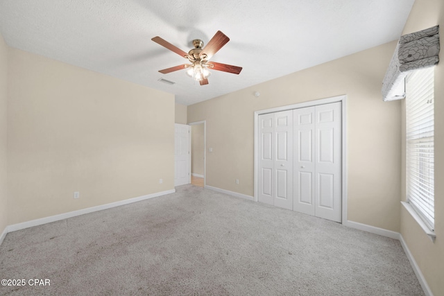 unfurnished bedroom with ceiling fan, a closet, visible vents, carpet flooring, and baseboards