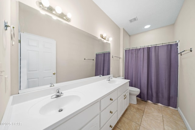 bathroom with a sink, tile patterned floors, double vanity, and toilet