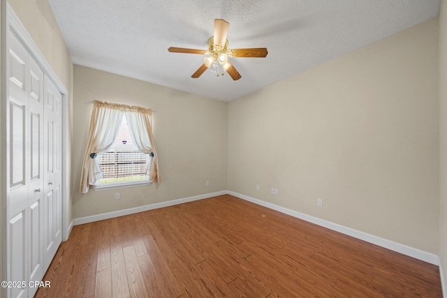 unfurnished room featuring ceiling fan, baseboards, a textured ceiling, and wood finished floors