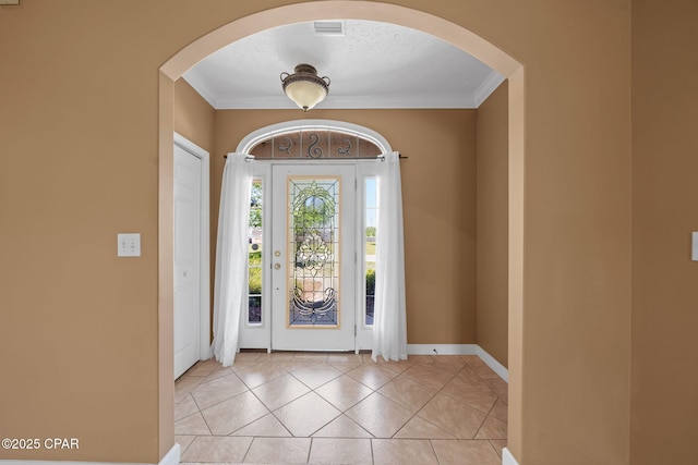 entryway with arched walkways, baseboards, crown molding, and light tile patterned flooring