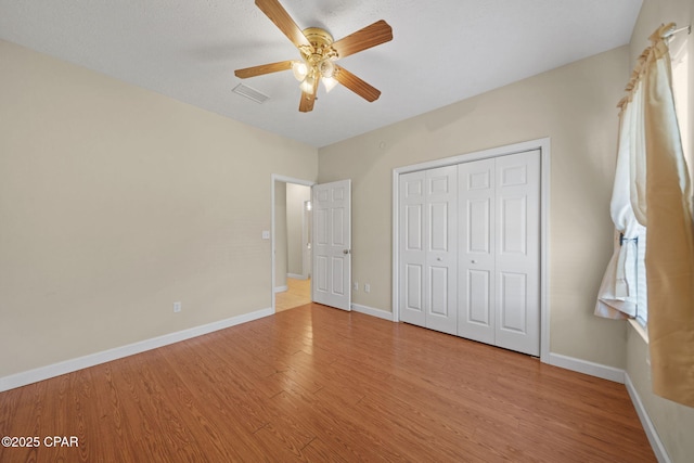 unfurnished bedroom with a closet, visible vents, baseboards, and wood finished floors