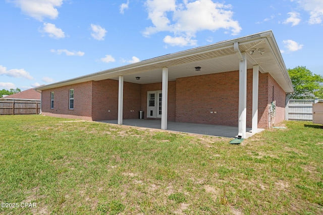 back of property with a yard, fence, brick siding, and a patio area