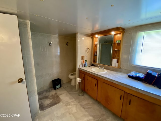 full bath featuring toilet, tile walls, vanity, and walk in shower