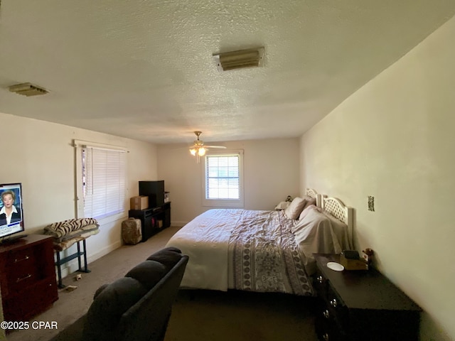 bedroom with a textured ceiling, visible vents, a ceiling fan, and carpet