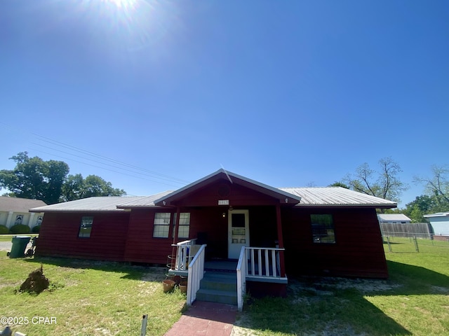 view of front facade featuring metal roof, fence, a front lawn, and covered porch