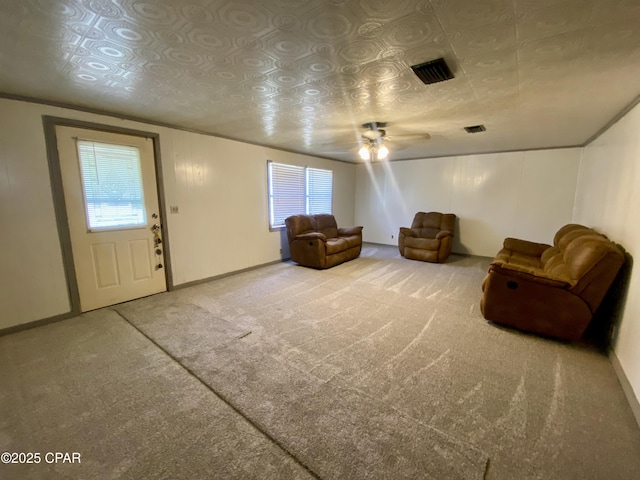 living area with carpet flooring, a ceiling fan, visible vents, and plenty of natural light