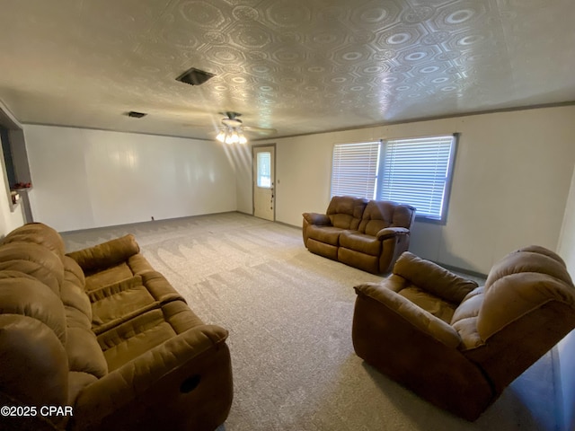 living room featuring visible vents, light colored carpet, and a ceiling fan