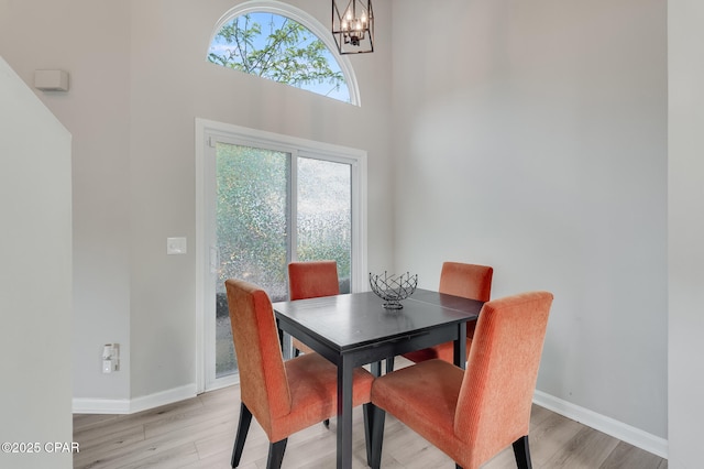 dining space with light wood finished floors, baseboards, a wealth of natural light, and a chandelier