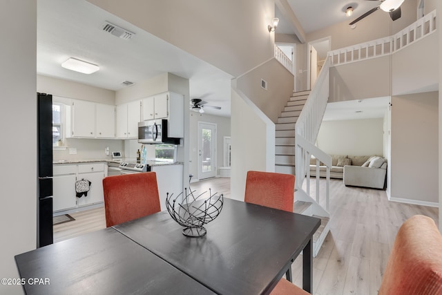 dining room featuring a ceiling fan, stairs, visible vents, and light wood-type flooring