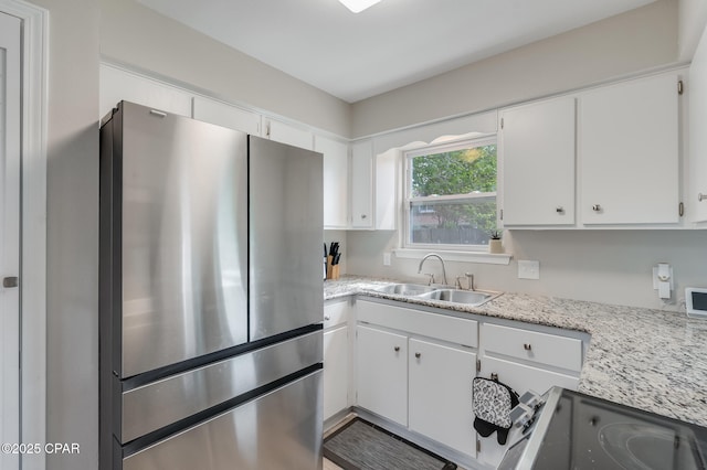 kitchen with range with electric cooktop, white cabinetry, a sink, and freestanding refrigerator