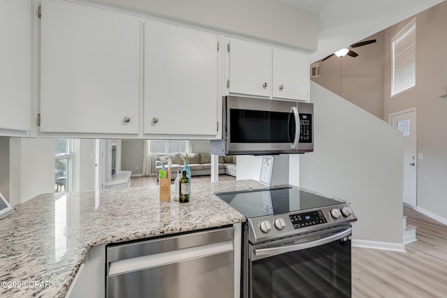 kitchen with white cabinets, a ceiling fan, light stone countertops, light wood-style flooring, and appliances with stainless steel finishes