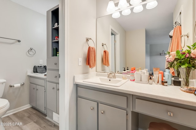 bathroom featuring baseboards, wood finished floors, vanity, and toilet