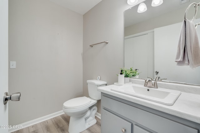 bathroom featuring wood finished floors, vanity, toilet, and baseboards