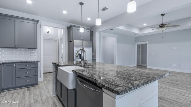 kitchen with dark stone counters, ceiling fan, visible vents, appliances with stainless steel finishes, and an island with sink