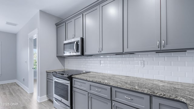kitchen with tasteful backsplash, appliances with stainless steel finishes, light wood finished floors, gray cabinetry, and visible vents