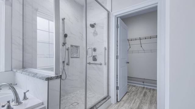 full bathroom with a garden tub, a marble finish shower, wood finished floors, and a spacious closet