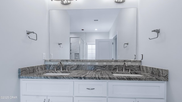 bathroom with a stall shower, double vanity, a sink, and visible vents