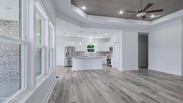 1113 New Hampshire Ave, Lynn Haven, FL 32444 - unfurnished living room with wood ceiling, light wood-style flooring, a tray ceiling, baseboards, and a ceiling fan