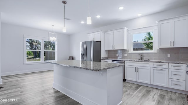 1113 New Hampshire Ave, Lynn Haven, FL 32444 - kitchen featuring light stone counters, stainless steel fridge, a sink, white cabinetry, and a center island