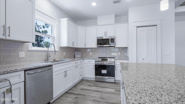 1113 New Hampshire Ave, Lynn Haven, FL 32444 - kitchen featuring light stone countertops, tasteful backsplash, stainless steel appliances, a sink, and white cabinetry