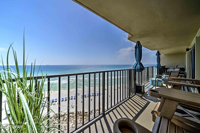 balcony featuring a view of the beach and a water view