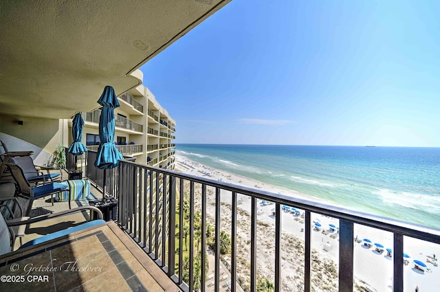 balcony featuring a view of the beach and a water view