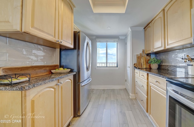 kitchen with light wood-style floors, decorative backsplash, light brown cabinets, and stainless steel appliances