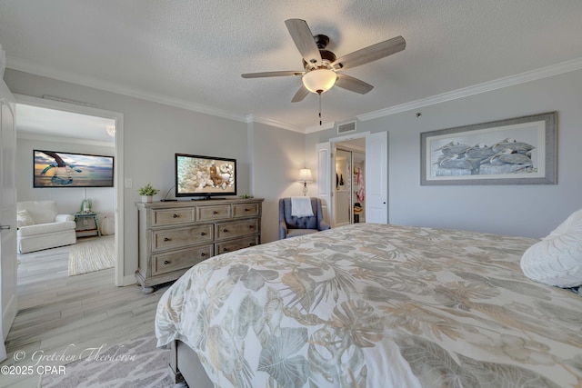 bedroom with crown molding, a textured ceiling, visible vents, and light wood-style flooring