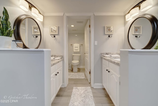 full bathroom featuring crown molding, two vanities, and toilet