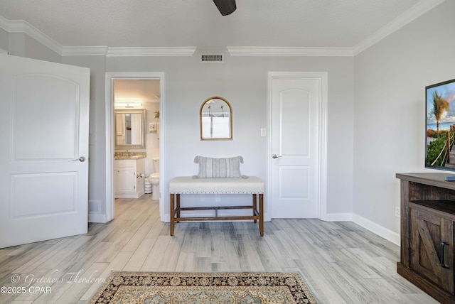 interior space with baseboards, crown molding, light wood finished floors, and visible vents