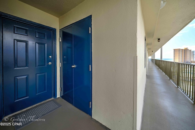 property entrance featuring stucco siding and a balcony