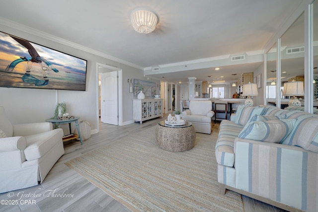 living area featuring visible vents, baseboards, and ornamental molding
