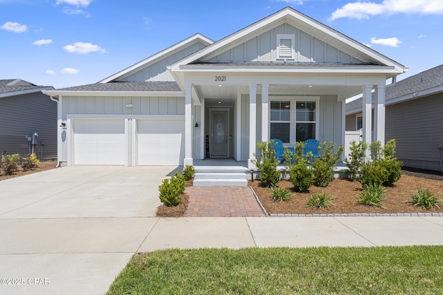 view of front of house with board and batten siding, an attached garage, covered porch, and driveway