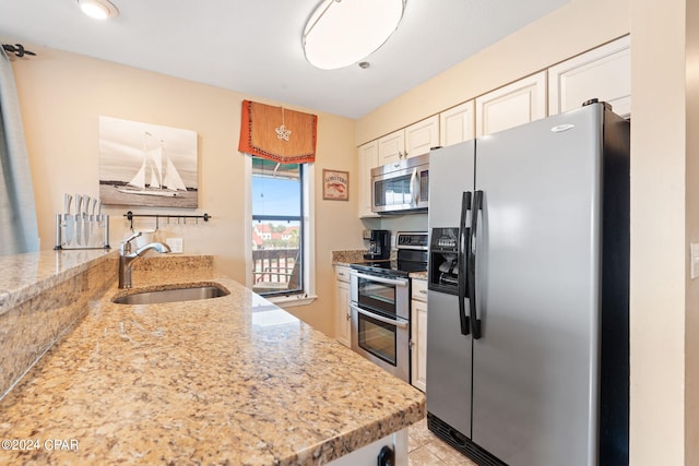 8730 Thomas Dr Unit 1311C, Panama City Beach, FL 32408 - kitchen with stainless steel appliances, light stone countertops, light tile patterned flooring, and white cabinets