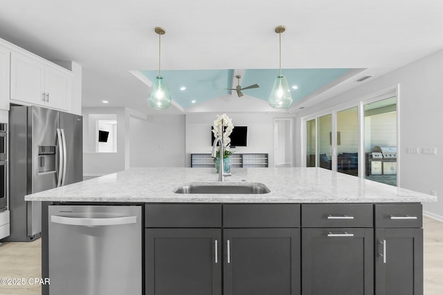 kitchen with light wood-style floors, light stone countertops, white cabinetry, appliances with stainless steel finishes, and a sink