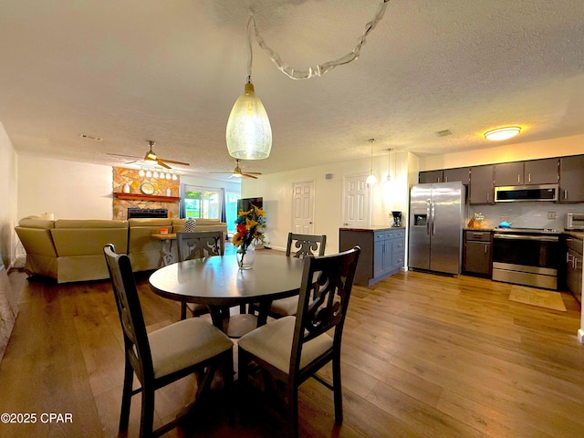 312 Sukoshi Dr, Panama City, FL 32404 - dining area featuring a ceiling fan, light wood-style floors, a textured ceiling, and a fireplace