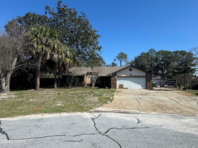 ranch-style home featuring an attached garage, concrete driveway, a front yard, and brick siding