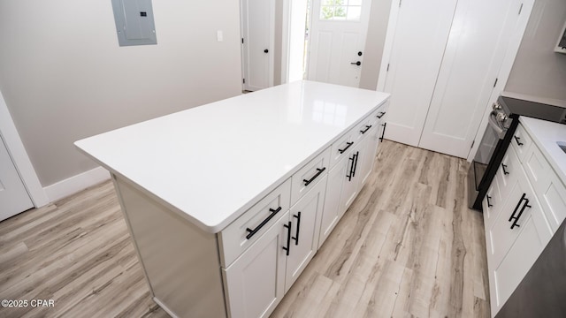 6401 Chipewa St, Panama City, FL 32404 - kitchen featuring stainless steel range with electric stovetop, electric panel, a kitchen island, light countertops, and light wood finished floors