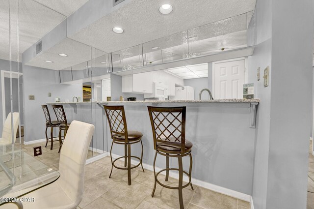 520 Richard Jackson Blvd Unit 2005, Panama City Beach, FL 32407 - kitchen with a textured ceiling, visible vents, baseboards, tile patterned floors, and freestanding refrigerator