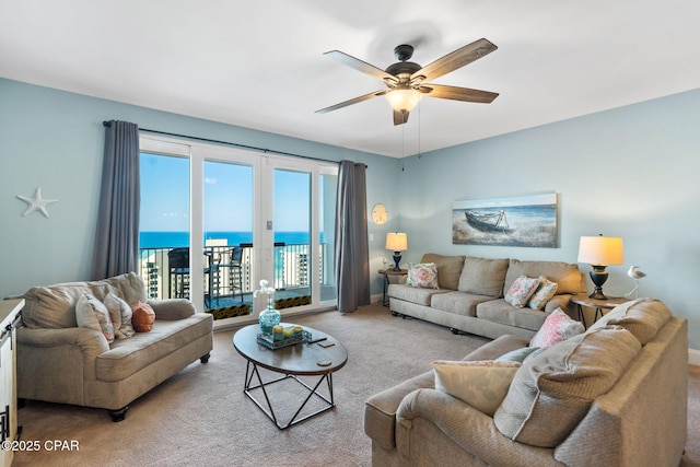 living room featuring a ceiling fan, a water view, carpet floors, french doors, and baseboards