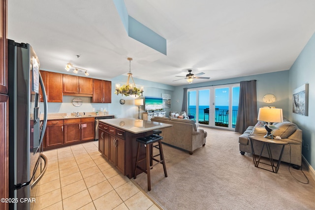 kitchen with stainless steel appliances, a breakfast bar, a kitchen island, open floor plan, and ceiling fan with notable chandelier